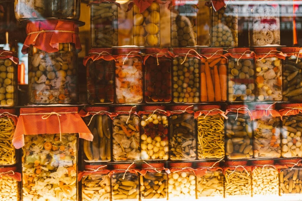 Rows of colorful preserved vegetables in glass jars, showcasing variety and abundance.